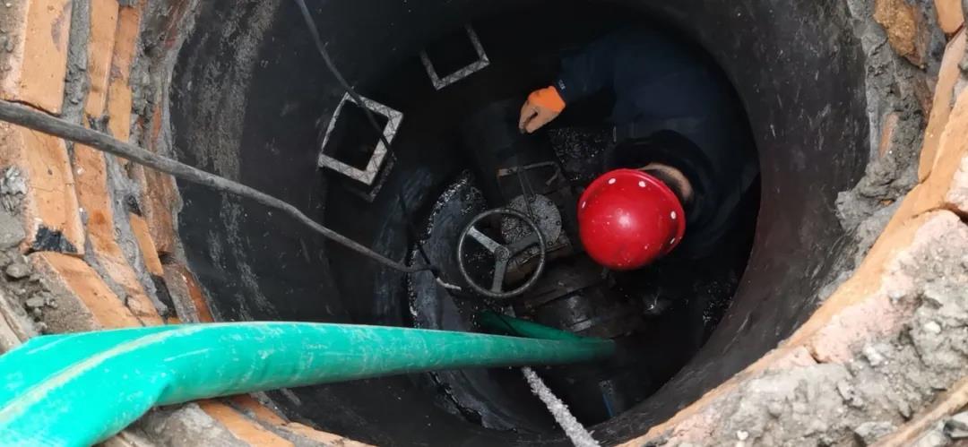 刺骨的寒风中,维修工人身着水皮裤,在管道井半米深的